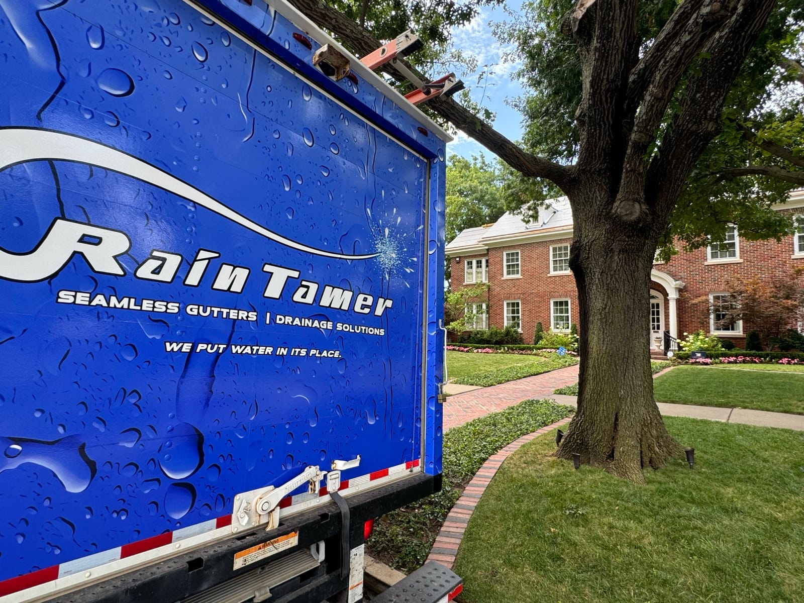 Rain Tamer truck logo with a colonial home in the background.